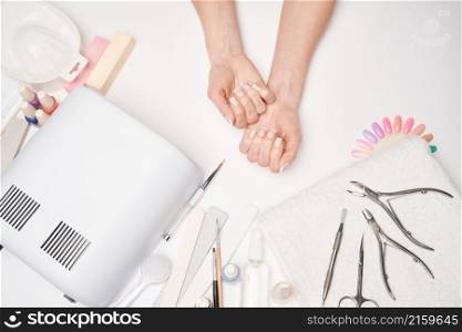 manicure and pedicure items - nail polish drying lamp, nail file, scissors and brushes over light background.. manicure and pedicure items - nail polish drying lamp, nail file, scissors and brushes over light background