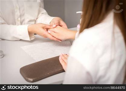Manicure master massaging female hands before nail procedure in a nail salon. Manicure master massaging female hands before nail procedure in a nail salon.