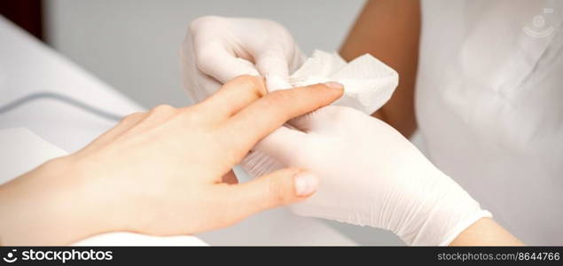 Manicure master wiping the moisturizer from the end of female fingers in beauty salon. Manicure master wiping the moisturizer from the end of female fingers in beauty salon.