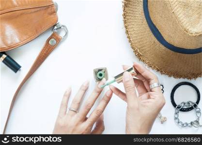 Manicure process. Nail polish being applied to hand, polish is a green color. Woman accessories on white background