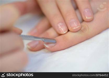 manicurist filing persons nails in salon