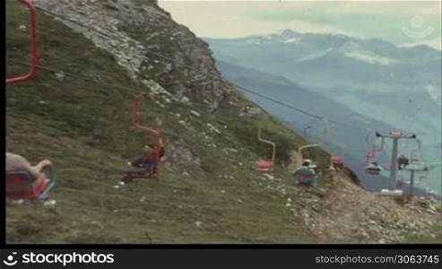 Mann fahrt mit dem Sessellift den Berg hinauf (8 mm-Film)