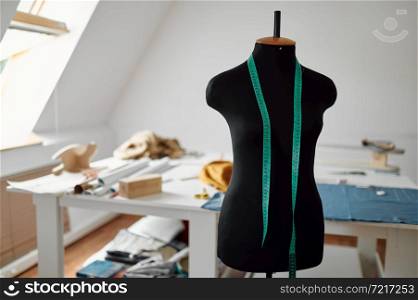 Mannequin in clothing workshop, dressmaking concept, tools on the table on background, nobody. Professional sewing, handmade tailoring business, handicraft hobby. Seamstress or dressmaker accessory. Mannequin in workshop, dressmaking concept, nobody