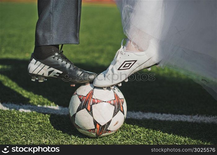 Mans and zhensy feet in football boots stand on a football.