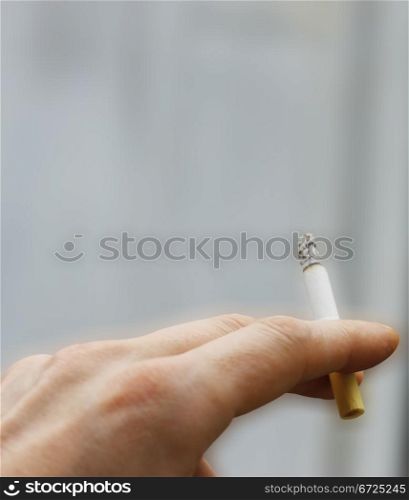 Mans hand hold a cigarette with a ash isolated
