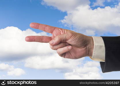 Mans hand, showing two fingers, cloudy blue sky background.