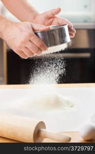mans hands sifting flour through a sieve for baking