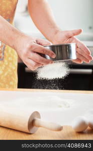 mans hands sifting flour through a sieve for baking