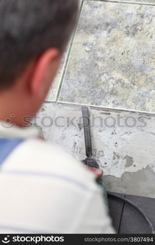 manual worker disassembling old floor tiles