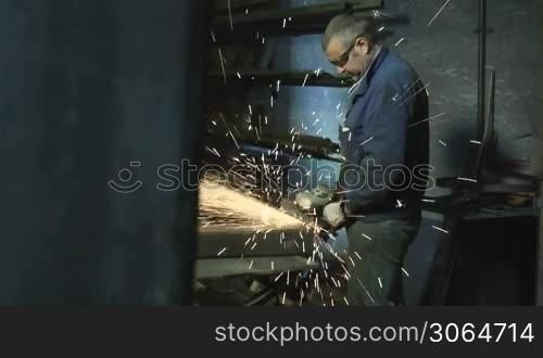 Manual worker in heavy industry using circular blade on a piece of metal. Dolly shot