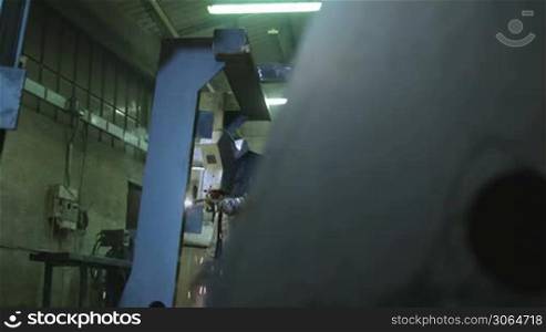 Manual worker in steel factory using welding mask, tools and equipment on metal. Dolly shot