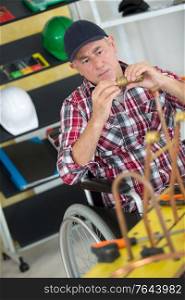 manual worker in wheelchair working with pipes