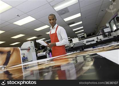 Manual worker looking down at prints