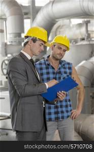 Manual worker with supervisor discussing over clipboard in industry
