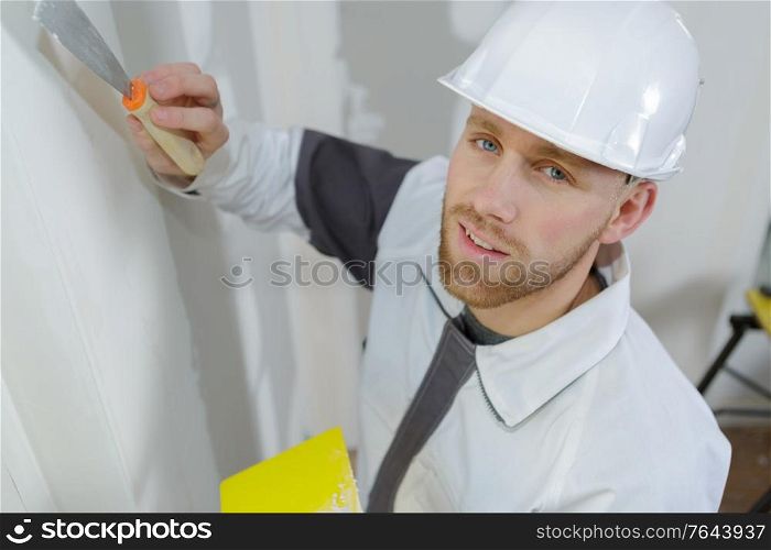 manual worker with wall plastering tools inside a house