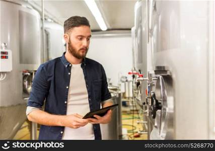 manufacture, business and people concept - man with tablet pc computer working at craft brewery or beer plant. man with tablet pc at craft brewery or beer plant