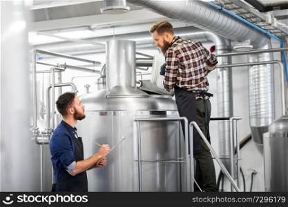manufacture, business and people concept - men with clipboard and malt working at brewery or beer plant kettle. men with clipboard at brewery kettle or beer plant