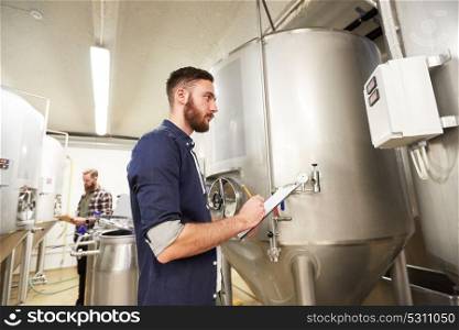 manufacture, business and people concept - men with clipboard working at craft brewery or non-alcoholic beer production plant. men with clipboard at craft brewery or beer plant