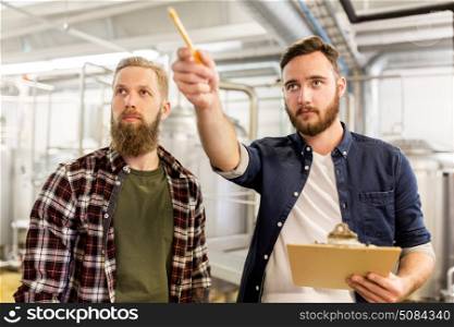 manufacture, business and people concept - men with clipboard working at craft brewery or beer plant. men with clipboard at craft brewery or beer plant. men with clipboard at craft brewery or beer plant
