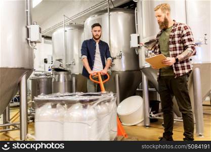 manufacture, business and people concept - men with malt bags on loader and clipboard working at craft brewery or beer plant. men with malt and clipboard at craft beer brewery. men with malt and clipboard at craft beer brewery