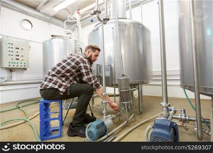manufacture, business and people concept - men working at craft brewery or non-alcoholic beer production plant. man working at craft beer brewery