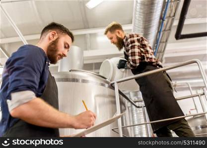 manufacture, business and people concept - men working at craft brewery or beer plant. men working at craft brewery or beer plant