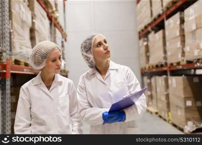 manufacture, industry and people concept - women technologists with clipboard at ice cream factory warehouse. women technologists at ice cream factory warehouse