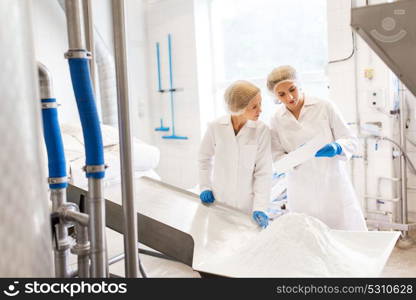 manufacture, industry, food production and people concept - women technologists with paper and powdered milk at ice cream factory shop. women technologists working at ice cream factory