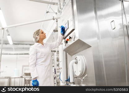 manufacture, industry, production and people concept - woman programming industrial equipment with computer at ice cream factory. woman programming computer at ice cream factory