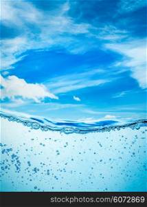 Many air bubbles in water close up, abstract water wave with bubbles on a background of blue sky