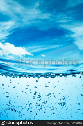 Many air bubbles in water close up, abstract water wave with bubbles on a background of blue sky