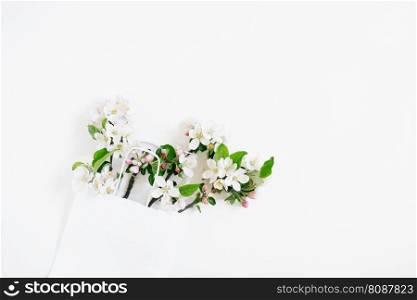 Many branches of an apple tree with flowers are in a paper shopping bag. Spring discounts and sales. Copy space, flat lay