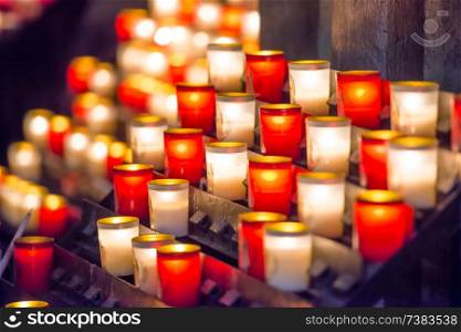 Many bright burning red and white candles in catholic church
