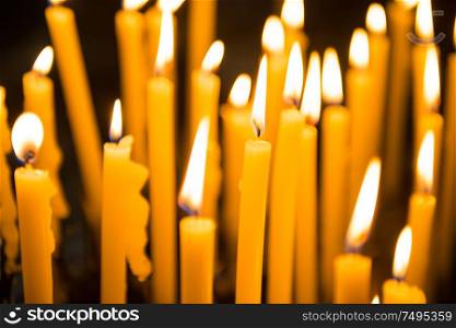 Many burning yellow wax candles in church. Venice, Italy