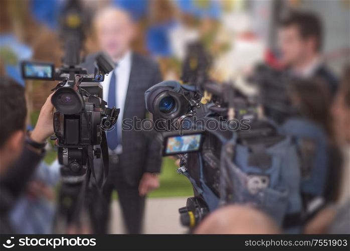 many cameras stand in a row at a press conference