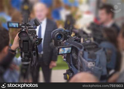 many cameras stand in a row at a press conference