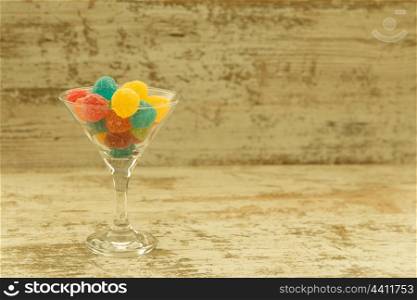 Many candy in glass with differents colors on wooden background