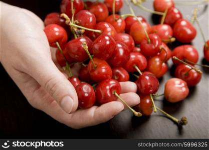 many cherries in a woman hand at a table