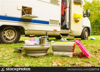 Many clean dishes drying outdoor against camper vehicle. Washing up on fresh air. Camping on nature, dishwashing outside.. Clean dishes drying on fresh air, camping outdoor