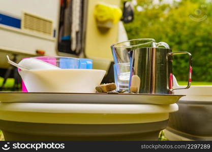 Many clean dishes drying outdoor against camper vehicle. Washing up on fresh air. Camping on nature, dishwashing outside.. Clean dishes drying on fresh air, camping outdoor