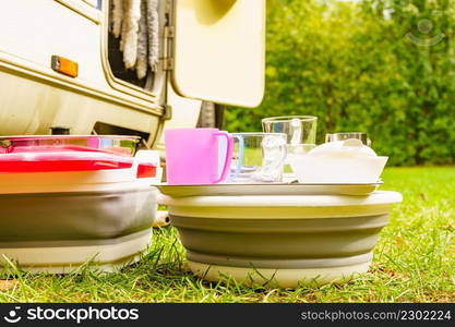 Many clean dishes drying outdoor against camper vehicle. Washing up on fresh air. Camping on nature, dishwashing outside.. Clean dishes drying on fresh air, camping outdoor