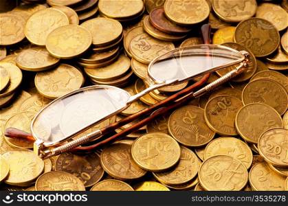Many coins and reading glasses as business concept