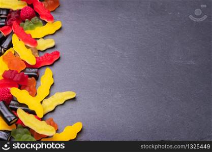 Many colored candies on dark background. Top view with copy space for your greetings.
