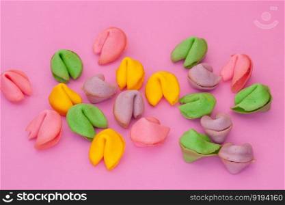 many colored cookies in the shape of seashells on a pink background. many colored cookies on a pink background