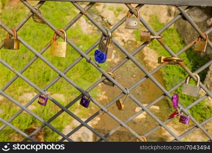 Many colorful metal love padlocks on fence