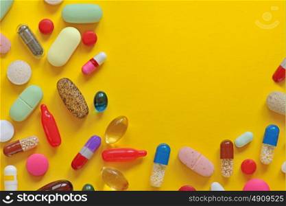 Many colorful pills isolated on yellow background