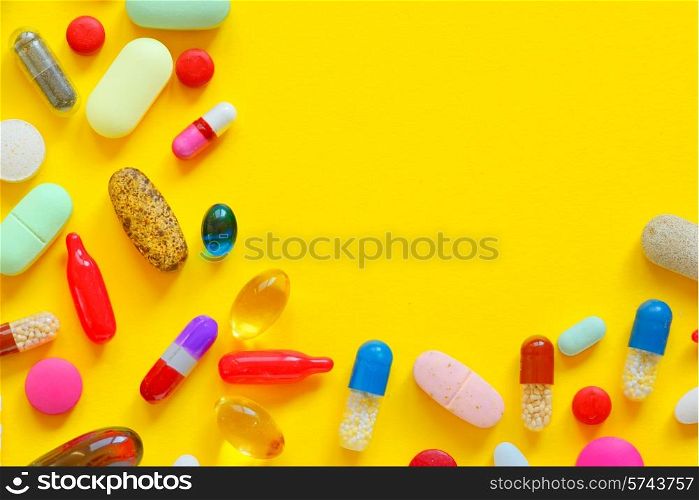 Many colorful pills isolated on yellow background