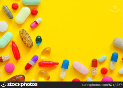 Many colorful pills isolated on yellow background