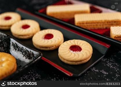 Many cookies are beautifully arranged in a plate and then placed on a wooden table.