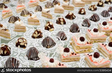 many cream sponge cakes and tapered sweets on buffet table, shallow DOF